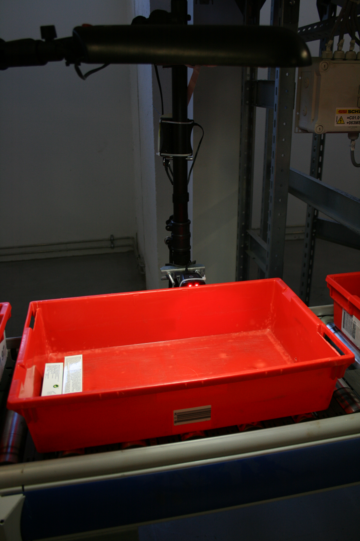 Befestigter Scanner, der gerade eine Wanne auf einem Förderband scannt